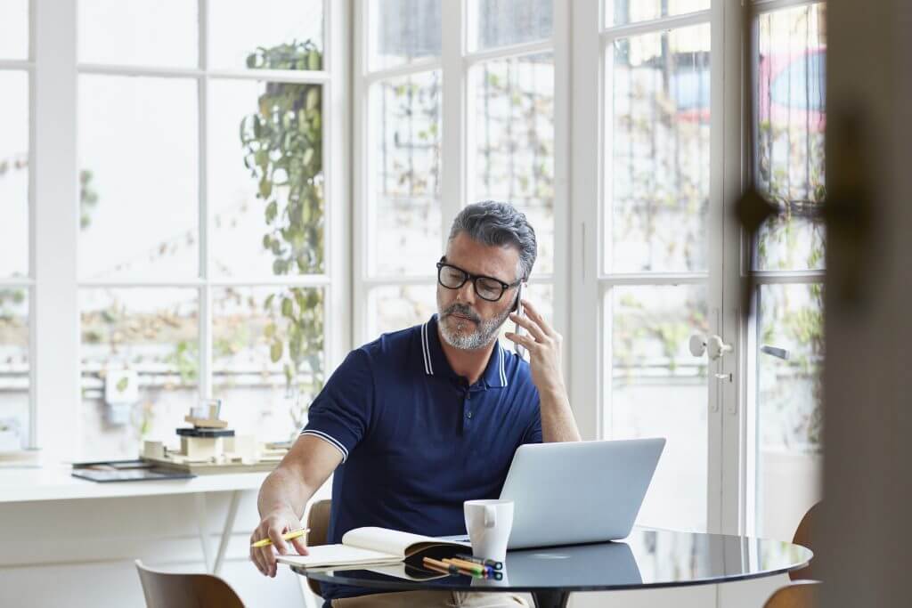 Man zit aan tafel in veranda en test of hij zijn telefoonnummer anoniem maakte