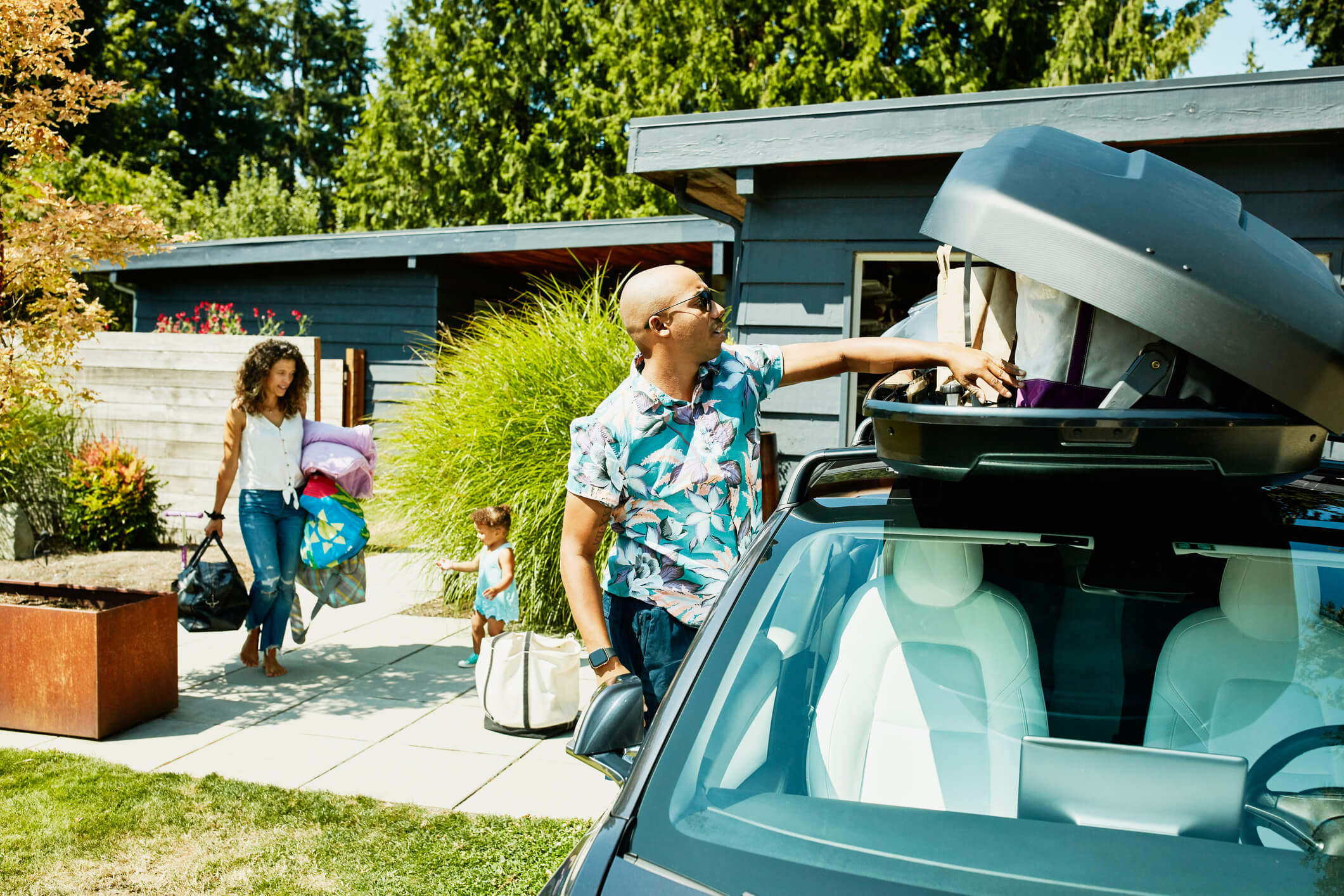 Man laadt dakkoffer van de auto om op reis te vertrekken