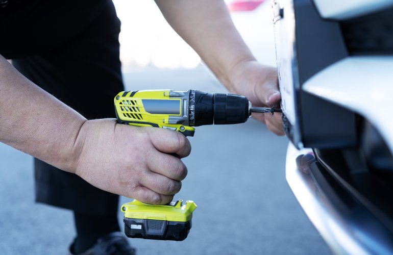 Man monteerd gepersonaliseerde nummerplaat