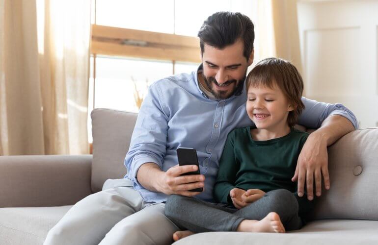 Vader en zoon kijken naar de smartphone.