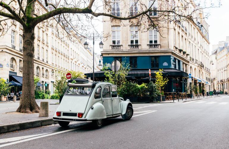 Lichtblauwe oldtimer staat in de zomer met opendak op straat in Parijs.