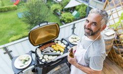 Man houdt een barbecue op het terras van zijn appartement