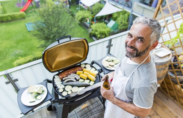 Man houdt een barbecue op het terras van zijn appartement