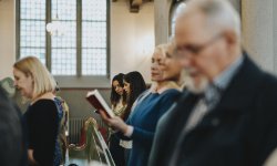 Familieleden van overledene zingen Afscheid van een vriend tijdens begrafenis in de kerk