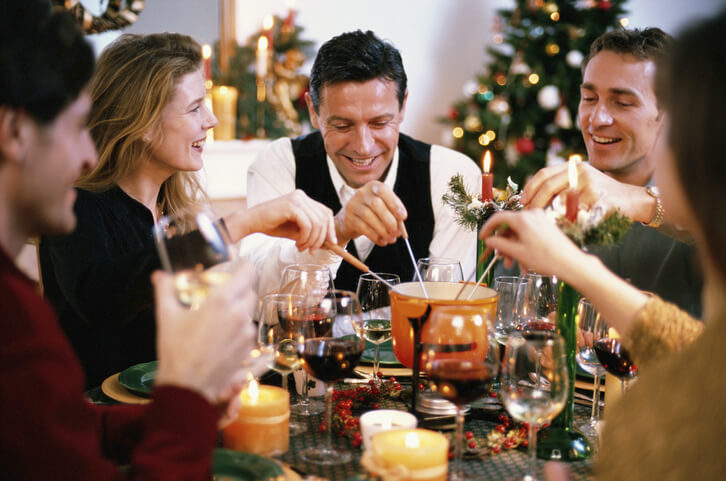 Mensen zitten rond tafel en eten fondue tijdens Kerstmis